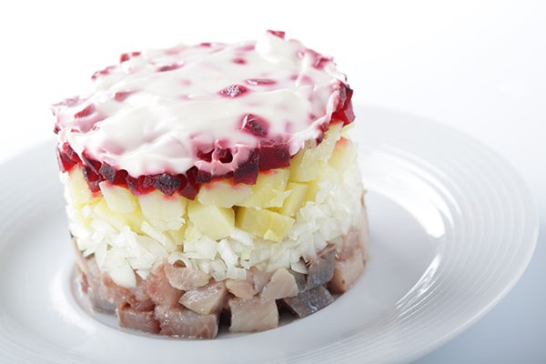 Russian herring salad with potatoes and beetroot on the white plate closeup